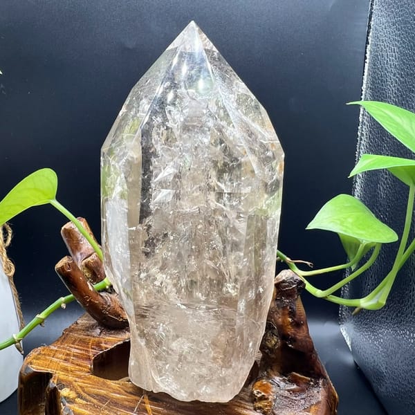 Large clear quartz point standing on its base full of enclosed crystals