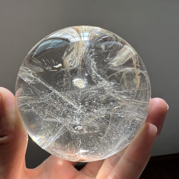 Mica coin and trailing flakes framed by curving cloud-like veils