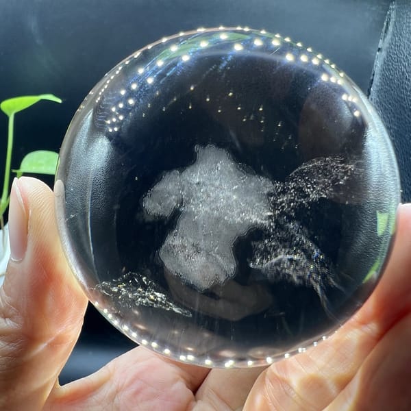 Smoky quartz ball with cloud inclusion and sparkling rim reflections