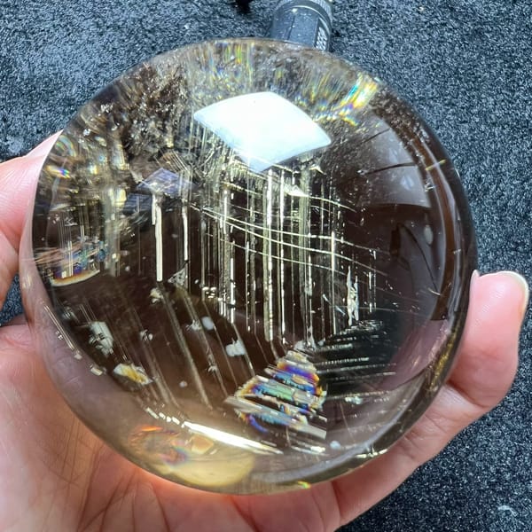Stepped black and silver phantom with rainbow edges rising near the base of the sphere