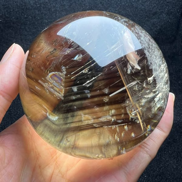 Honey-coloured glow through the lower half of the citrine sphere resting in a palm