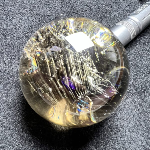 Torch-lit sphere showing a violet flash beside the vertical needle curtain