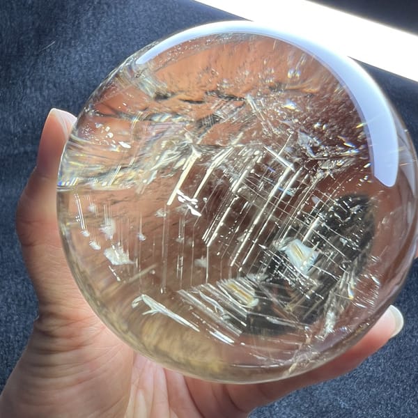 Overhead light reflected on the polished citrine with fine needles scattered below it