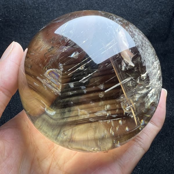 Smoky golden tones and a small rainbow pocket on the left side of the sphere