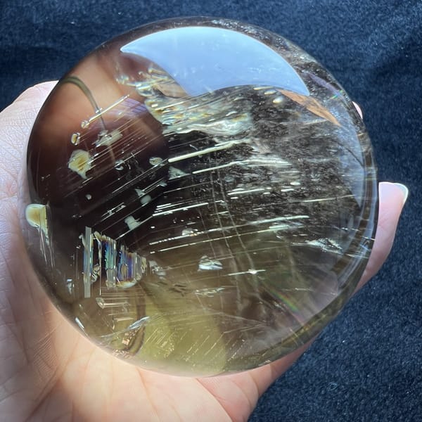 Opposite face of the citrine sphere showing small rainbow patches among the streaks