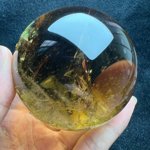 Darker smoky-gold upper half of the sphere above clearer yellow quartz