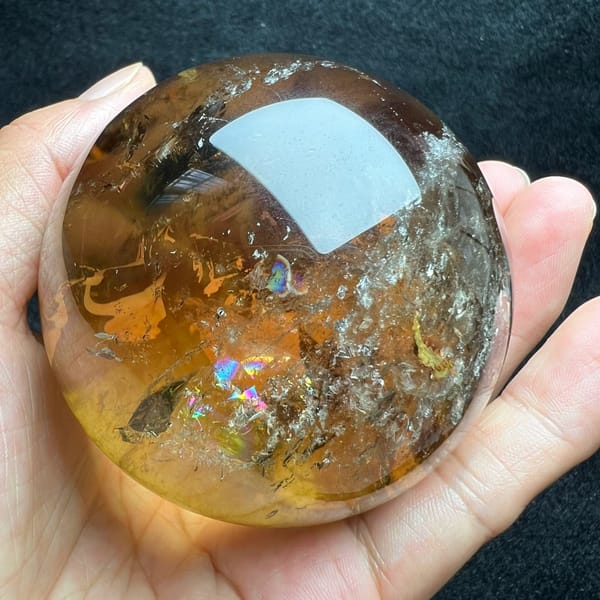 Side angle showing scattered gold glints and a rainbow patch in the citrine
