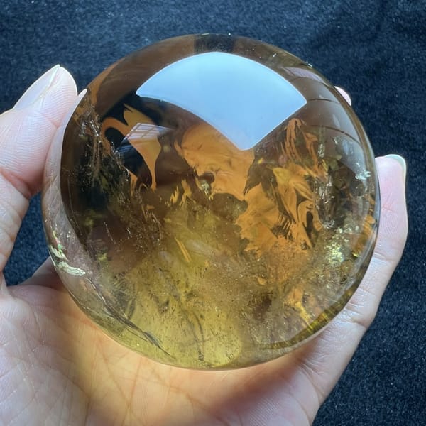 Amber-toned citrine sphere with swirling veils seen from a slightly raised angle