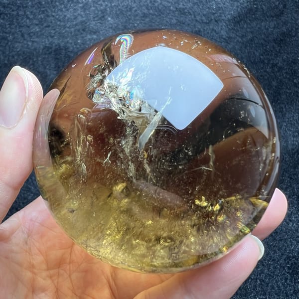 Frosty white feather inclusion near the top of the golden citrine sphere