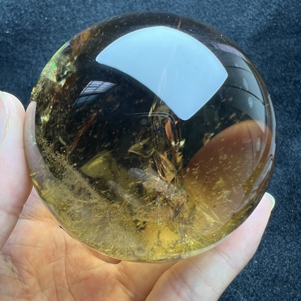 Fine gold glints scattered across the darker side of the citrine sphere