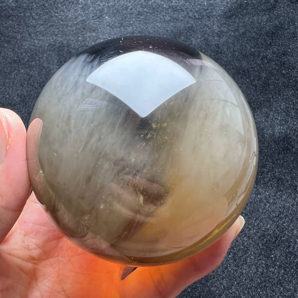 Smoky grey-brown side of the sphere with fine white needles visible inside