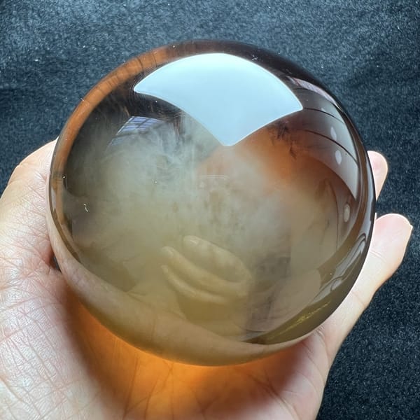 Warm amber light passing through the sphere onto the fingers below