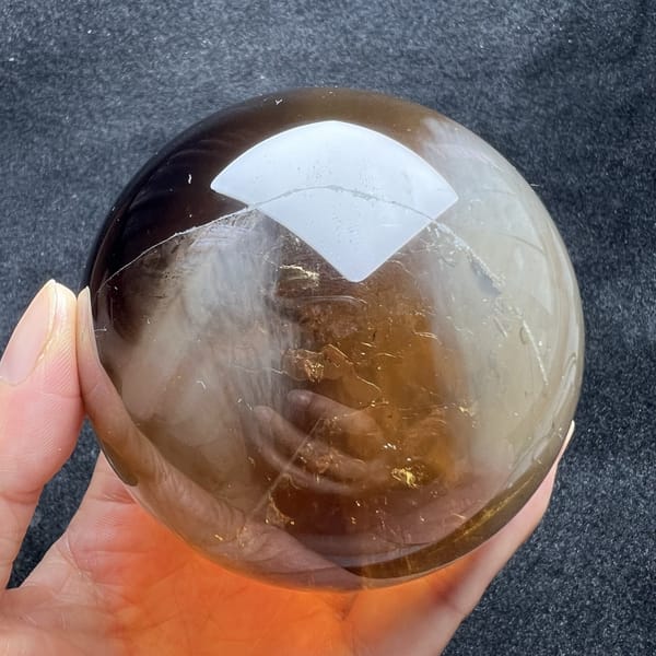 Brown tones and wispy white needles on another face of the citrine sphere