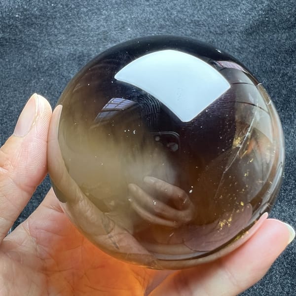 Dark smoky citrine face with soft white needles below the reflection