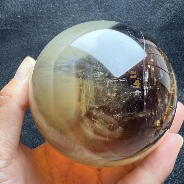 Glossy citrine sphere with smoky shading and golden flecks on one side