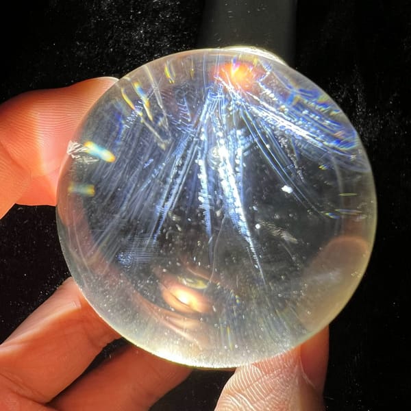 Feather-shaped blue needle fans spreading downward through the clear sphere