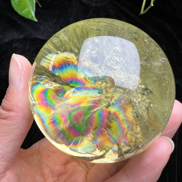 Bold rainbow bands spreading across the left half of the citrine sphere