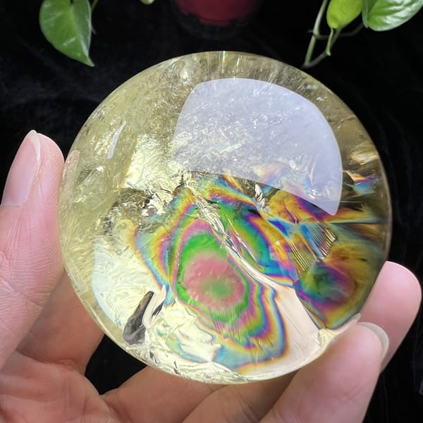 Rainbow rings beneath the reflection on the lemon-yellow sphere