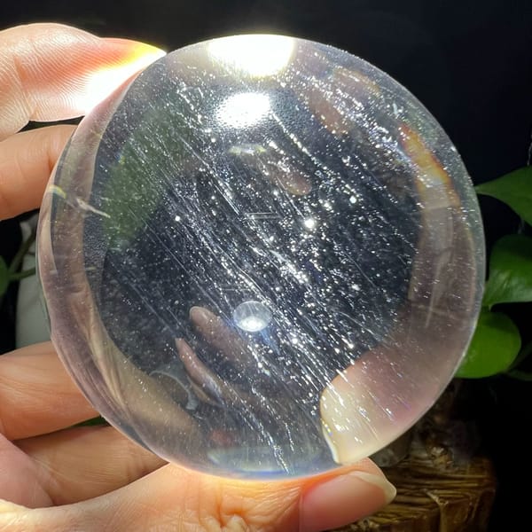 Backlit sphere revealing dense slanted silky streaks across the quartz