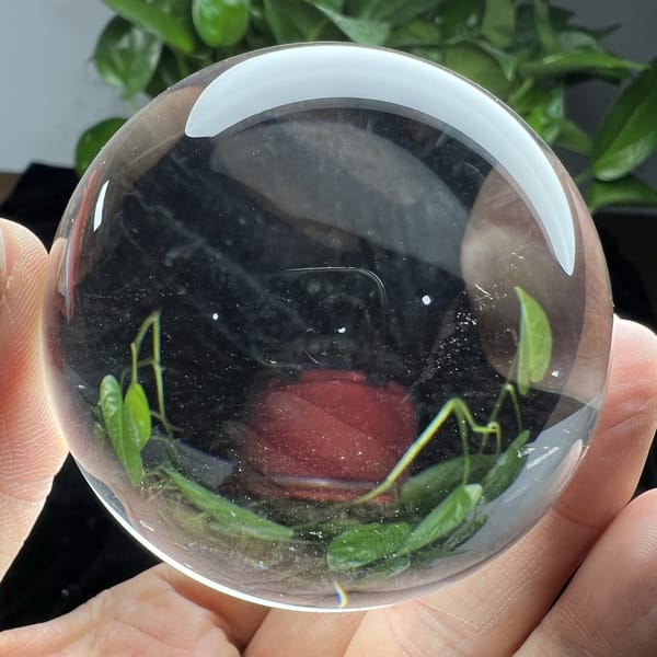 Transparent quartz sphere with refracted leaves and a red shape below