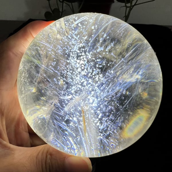 Layered silver phantom with a soft rainbow ring at the lower right