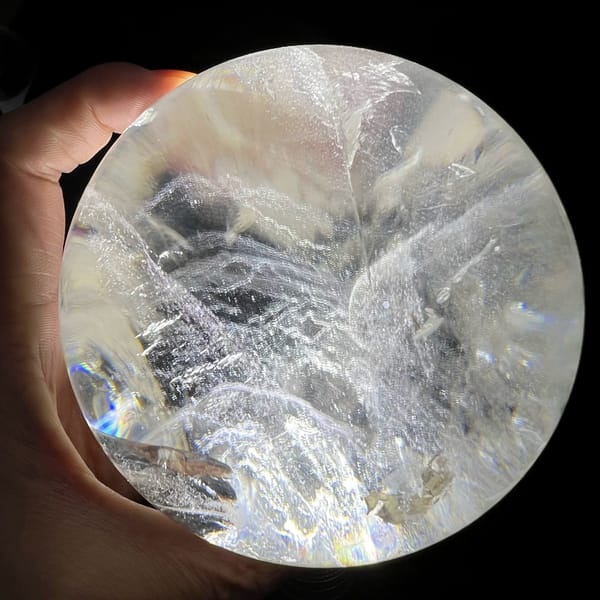 Large clear sphere in hand showing layered white phantom ridges across the middle