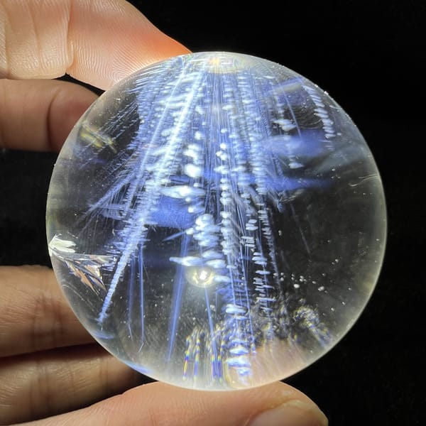 Vertical white beaded chains set among blue needles in the sphere