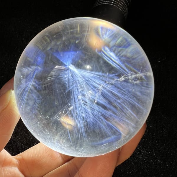 Single fan of blue needles radiating through pale clear quartz