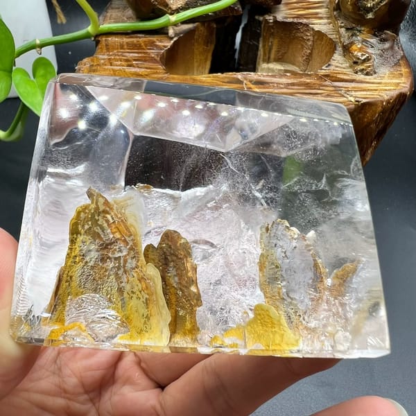 Golden peaks inside the quartz with a wooden root carving behind