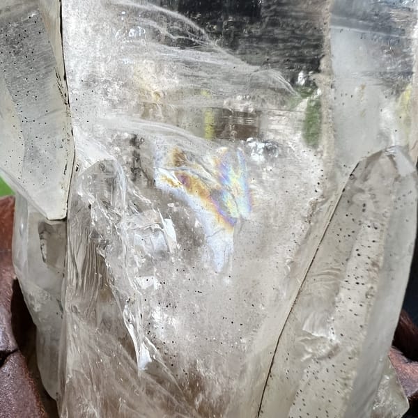 Close-up inside the quartz showing a rainbow, dark specks and soft veils