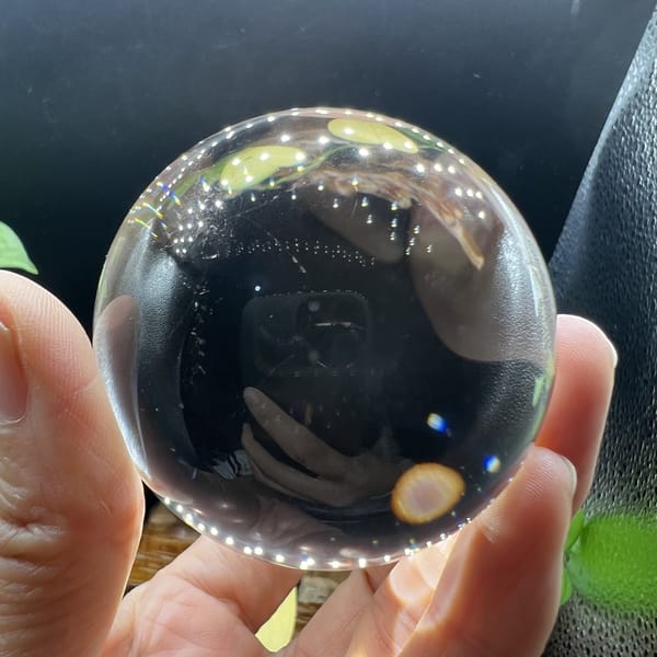 Sphere held up in daylight reflecting the photographer and window light