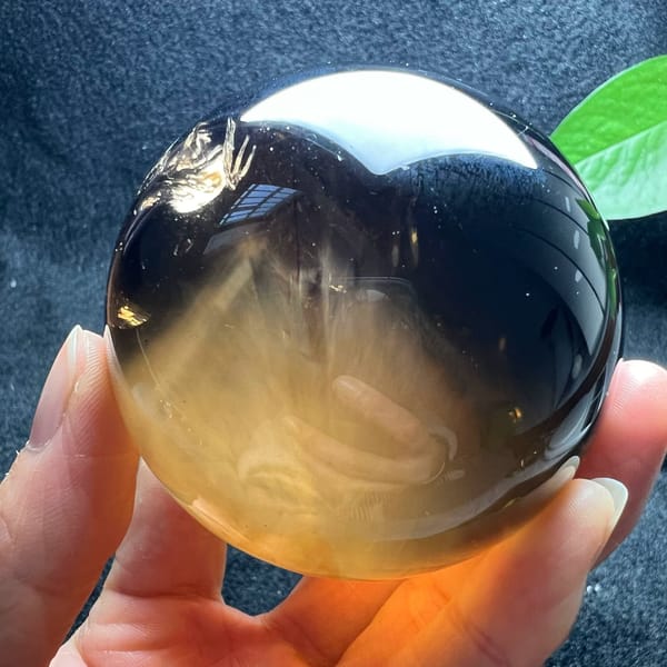 Smoky citrine sphere with a white needle mountain fanning up from the honey base