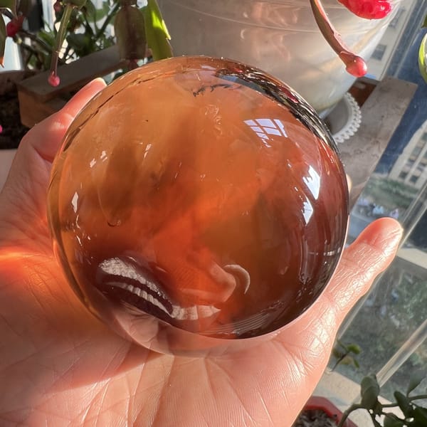 Sphere in sunlight showing deep orange and red tones by a window