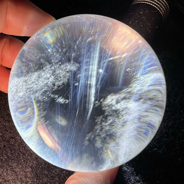 Long straight blue needle streaks crossing the clear quartz sphere