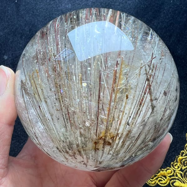 Large rutilated sphere with parallel reddish and golden needles fanning upward