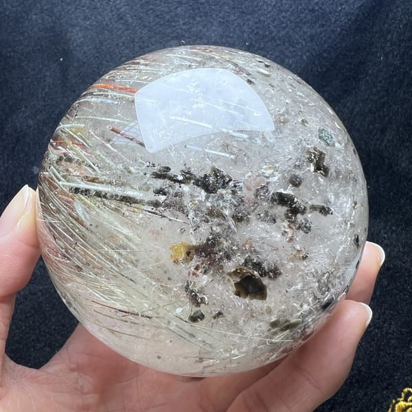 Dark and golden mica flakes clustered among fine rutile needles