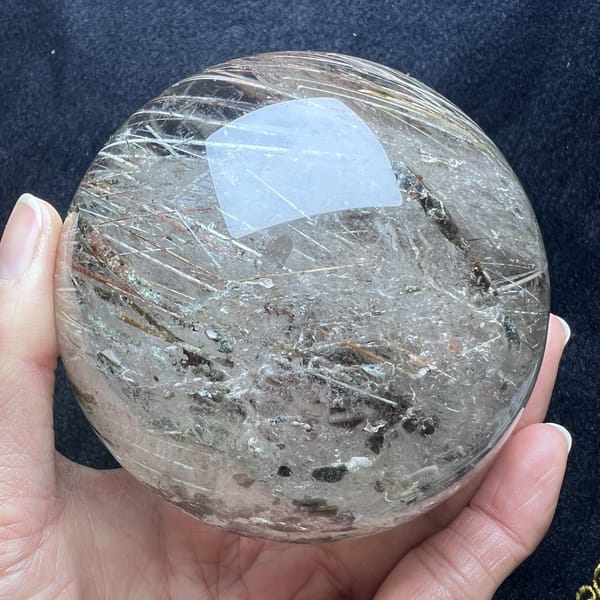 Mica flakes and pale needles scattered through the clear sphere