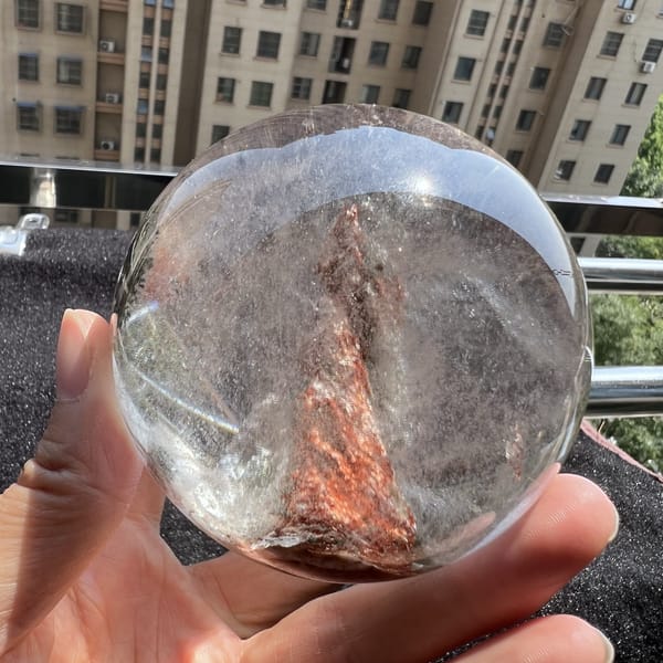 Copper-pink peak climbing through clear quartz in bright daylight
