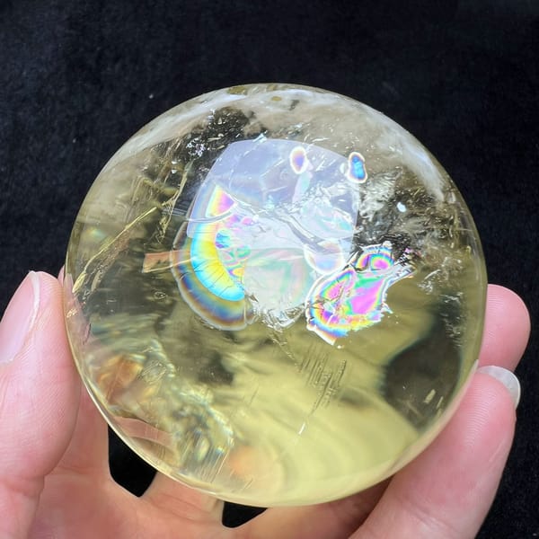 Rainbow patches clustered near the top of the clear citrine