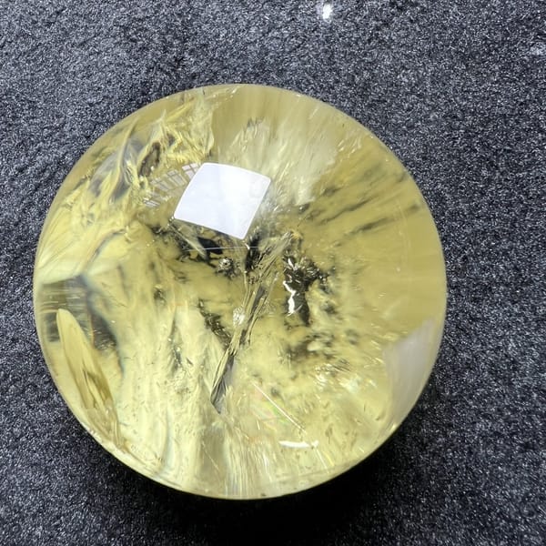 Citrine sphere on grey textured cloth with needles and veils inside