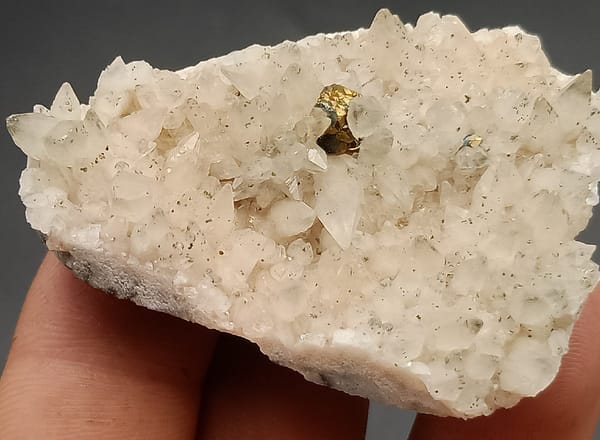 Goudkleurige pyrietkubus tussen witte calcietpunten