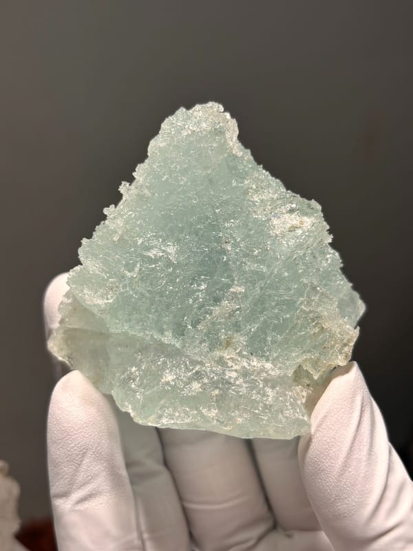 Etched aquamarine plate from Xuebaoding, Sichuan, China, held in gloved hand