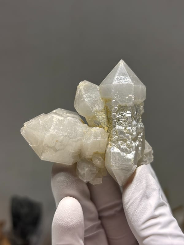 White sketch-pattern quartz cluster from Yunnan, China, held in gloved hand