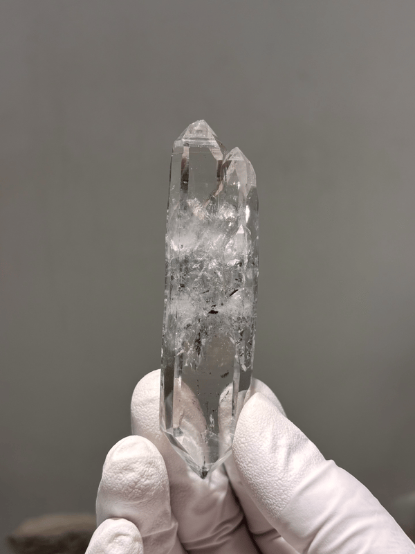 Double-terminated quartz with black inclusions from Jinkouhe, Sichuan, China, held in gloved hand