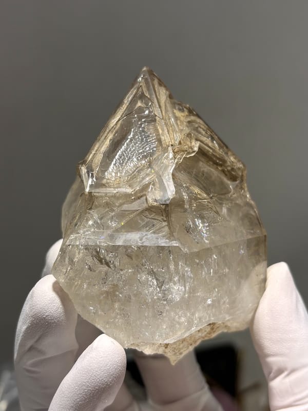 Large skeletal quartz with complete tip from Jinkouhe, Sichuan, China, held in gloved hand