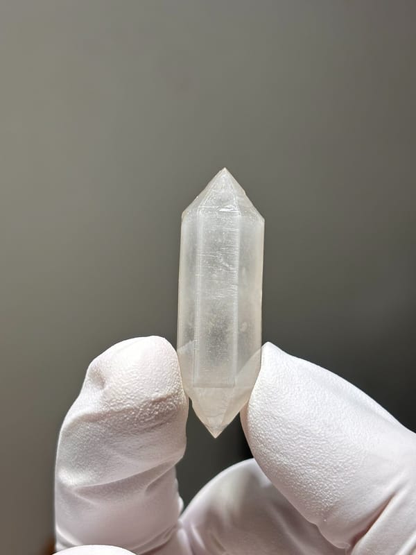 White porcelain sketch-pattern double-terminated quartz from Yunnan, China, held in gloved hand
