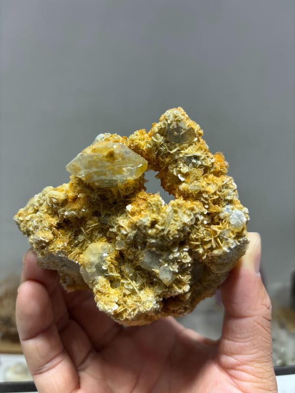 Pale aquamarine in golden mica with natural hollow from Xuebaoding, Sichuan, China, held in hand