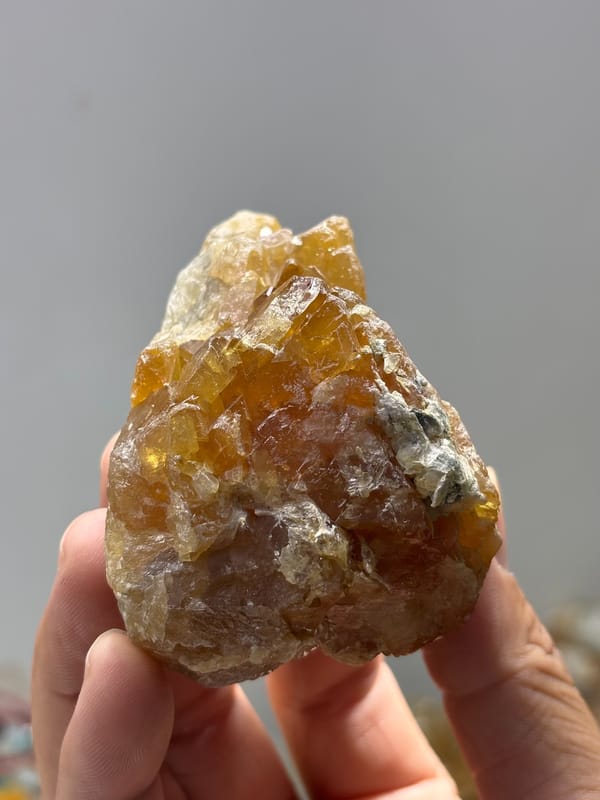Large honey-orange scheelite crystal from Xuebaoding, Sichuan, China, held in hand