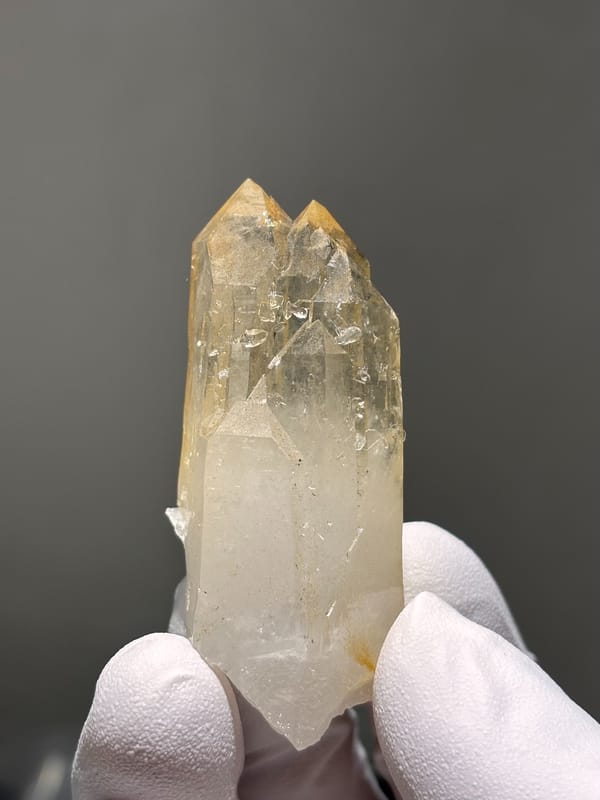 Pale golden cathedral quartz point from Xuebaoding, Sichuan, China, held in gloved hand