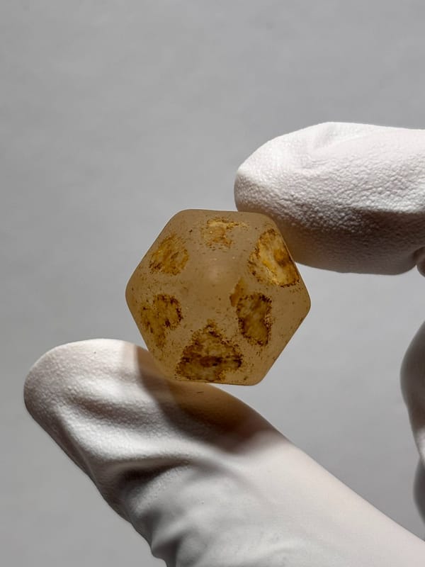 Six-window water-worn quartz with white cap from Yunnan, China, held in gloved hand
